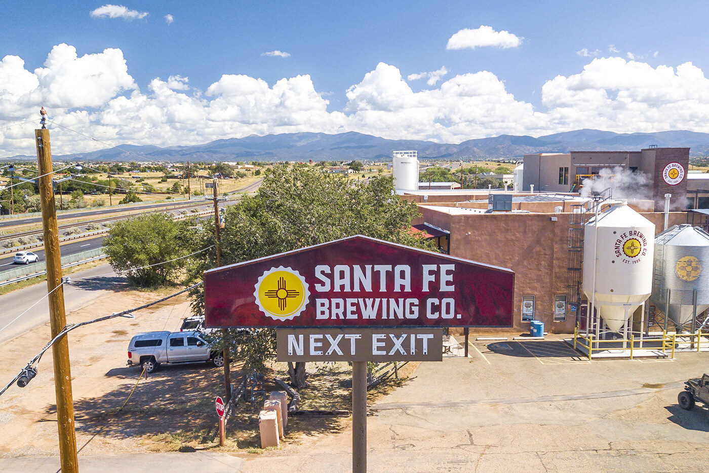 The Santa Fe Brewing Co. Next Exit sign with the brewery campus and mountains behind
