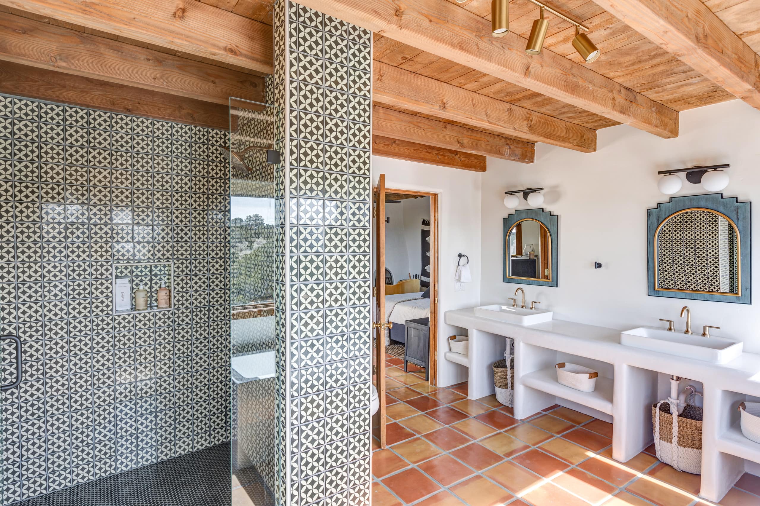 Bath with green-and-white patterned tile shower and plaster vanity