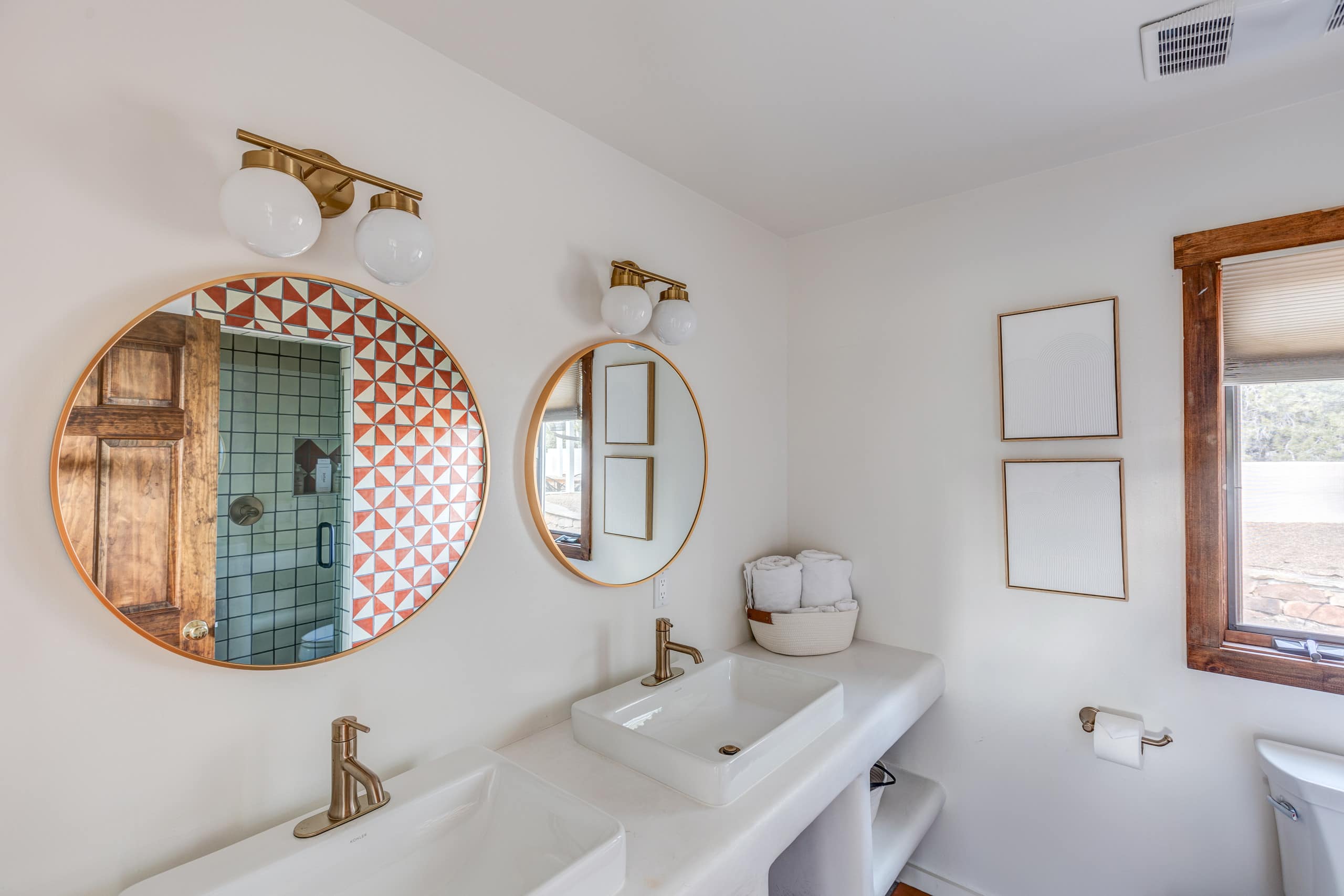 Double vessel-sink vanity with brass fittings and round mirrors
