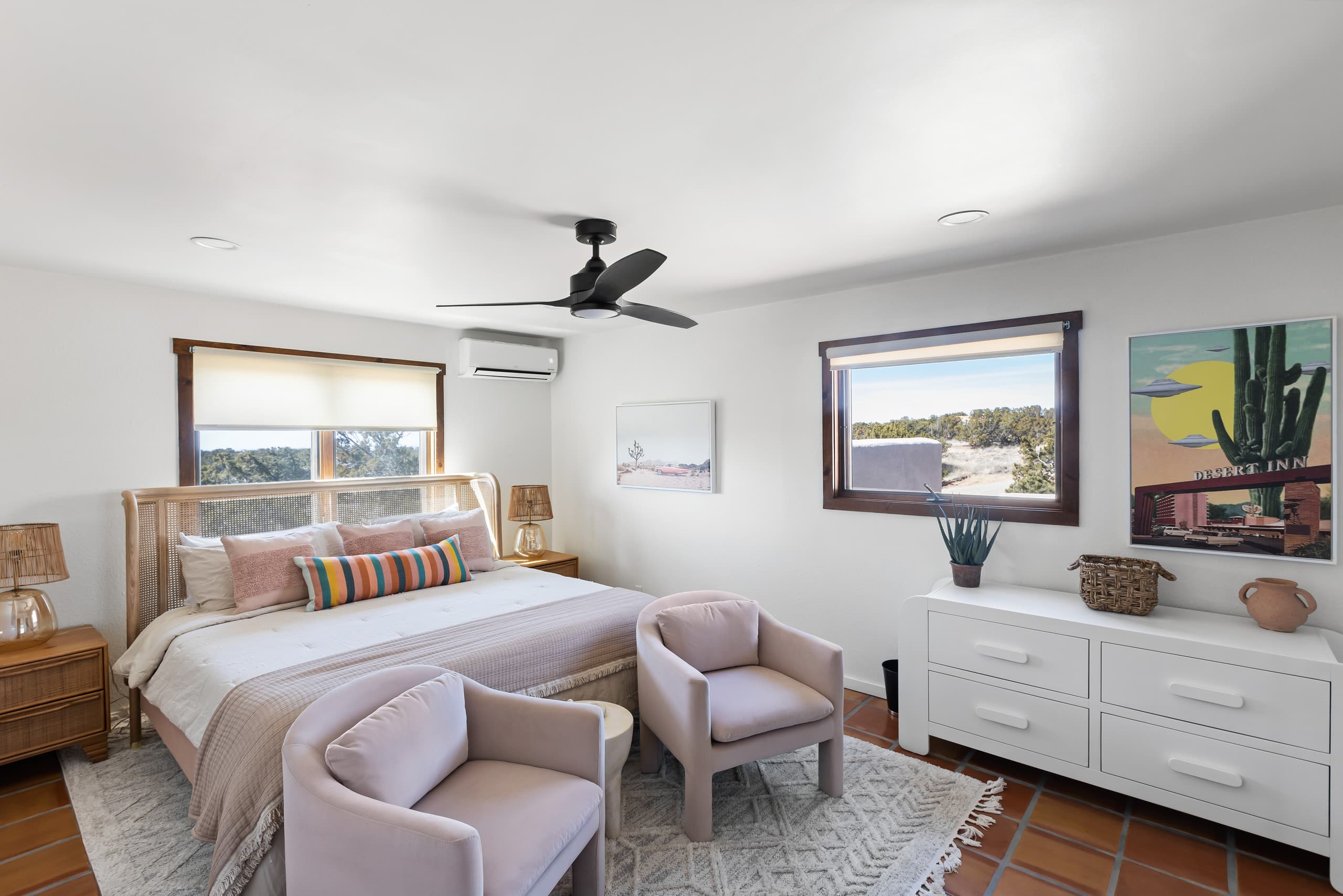 King bedroom with cane headboard and blush armchairs