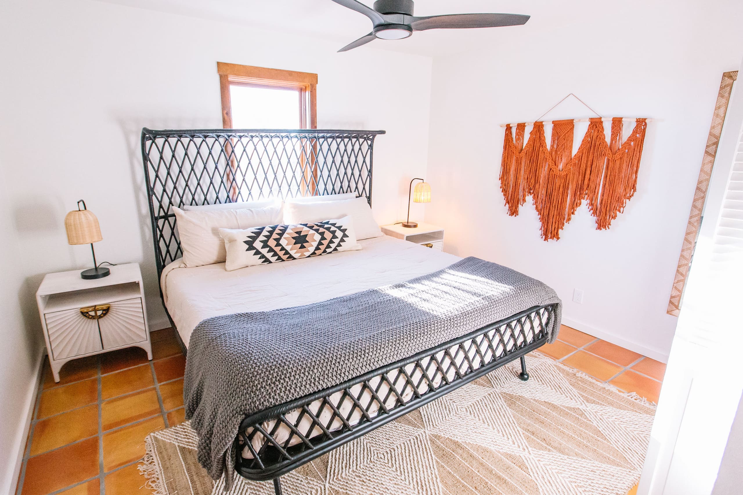 King bedroom with woven rattan bed and macrame wall hanging