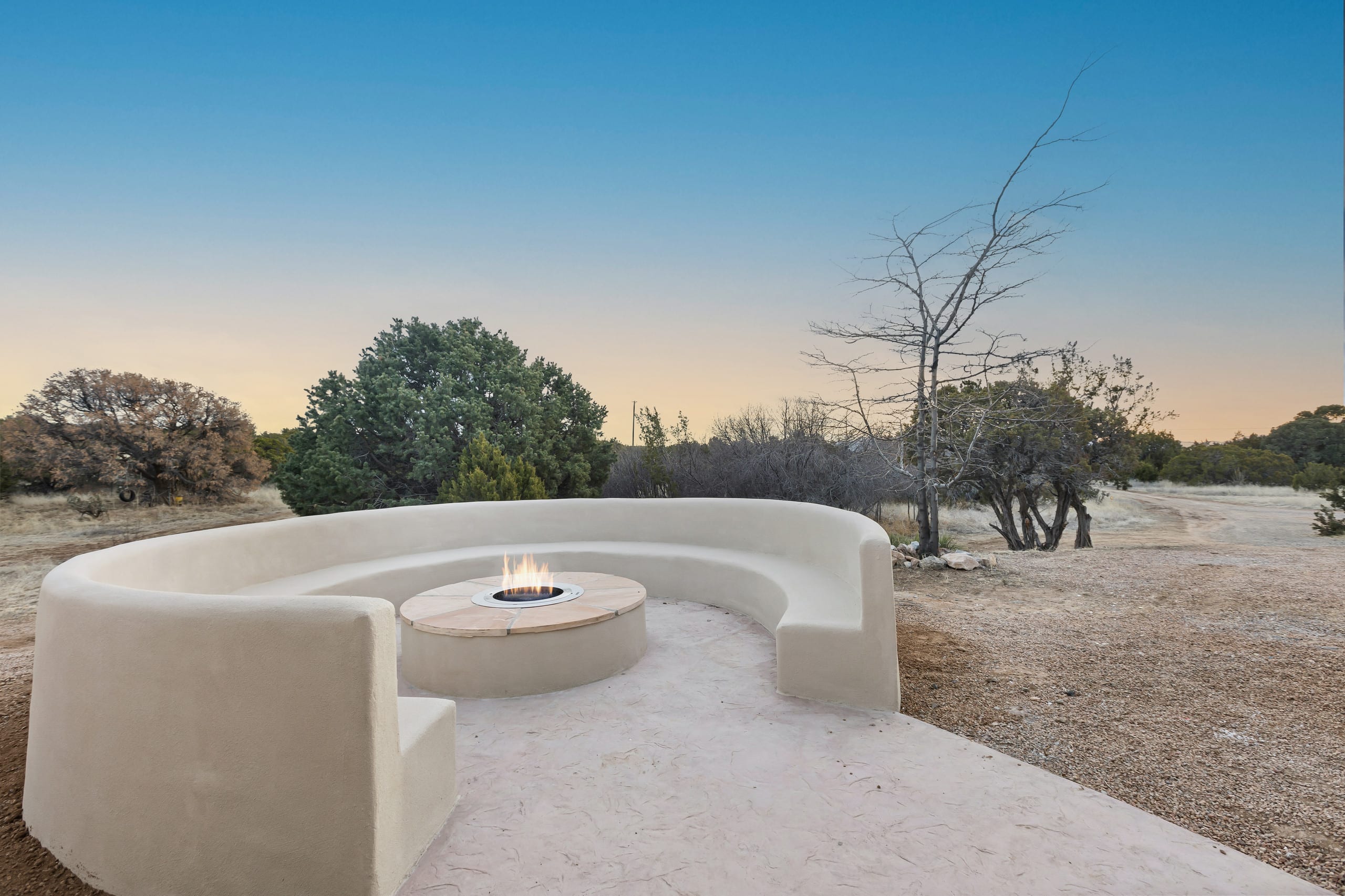 Circular stucco firepit court burning at dusk