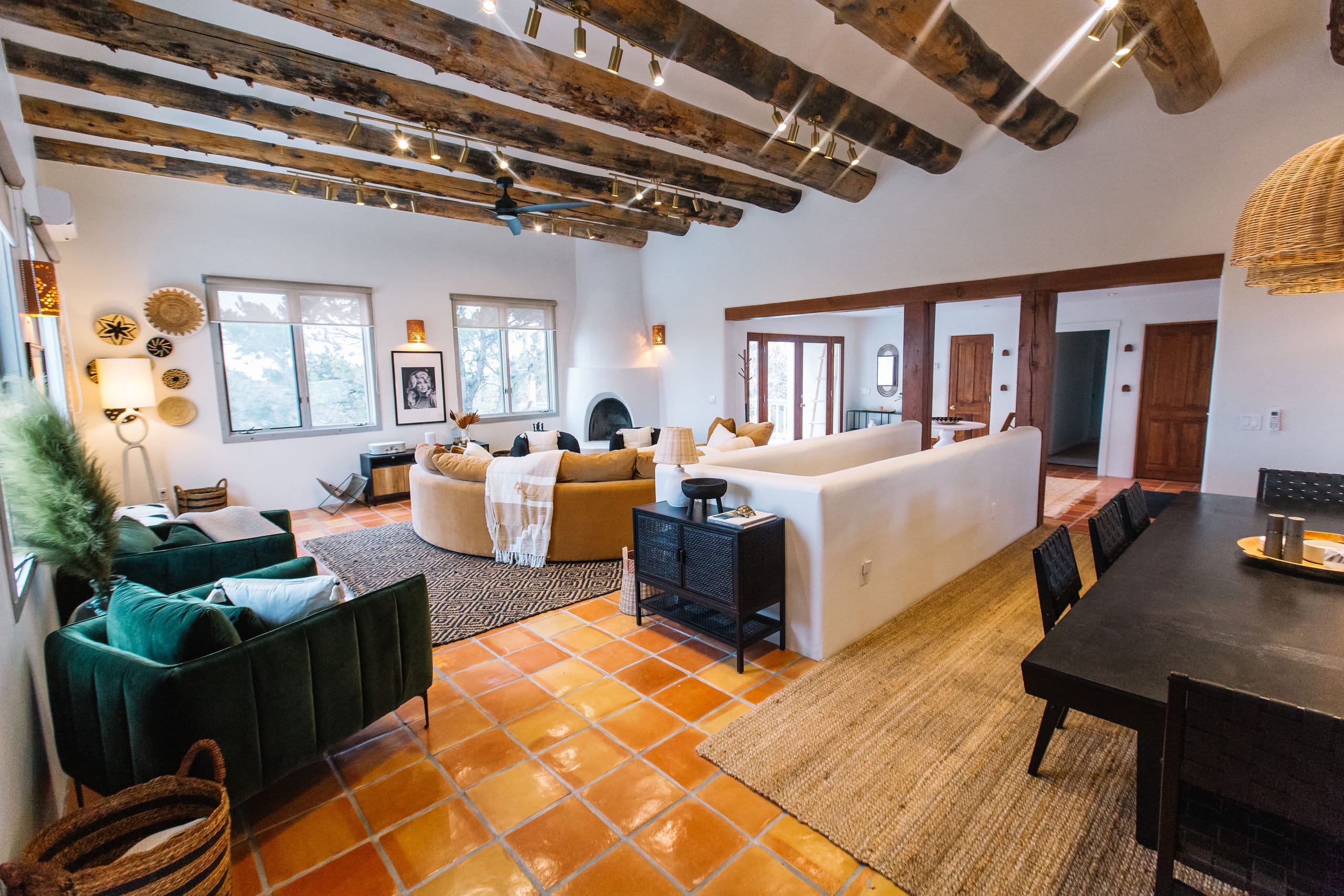 Great room from the dining end with green velvet sofas and beam ceiling