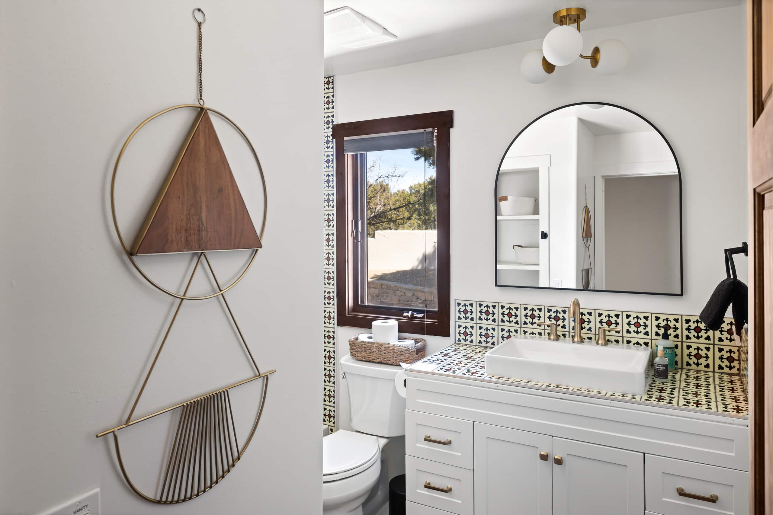 Half bath with green patterned tile and arched mirror