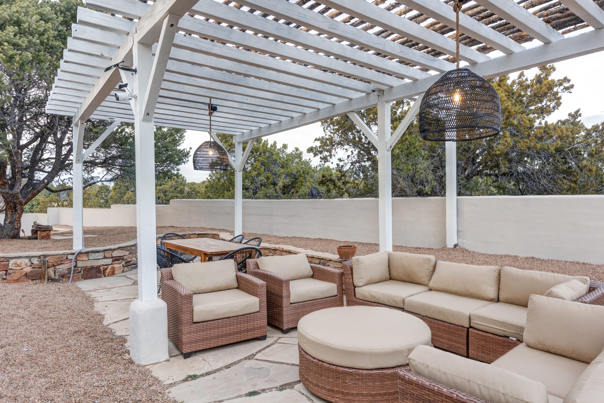 White pergola courtyard with outdoor dining and egg chairs