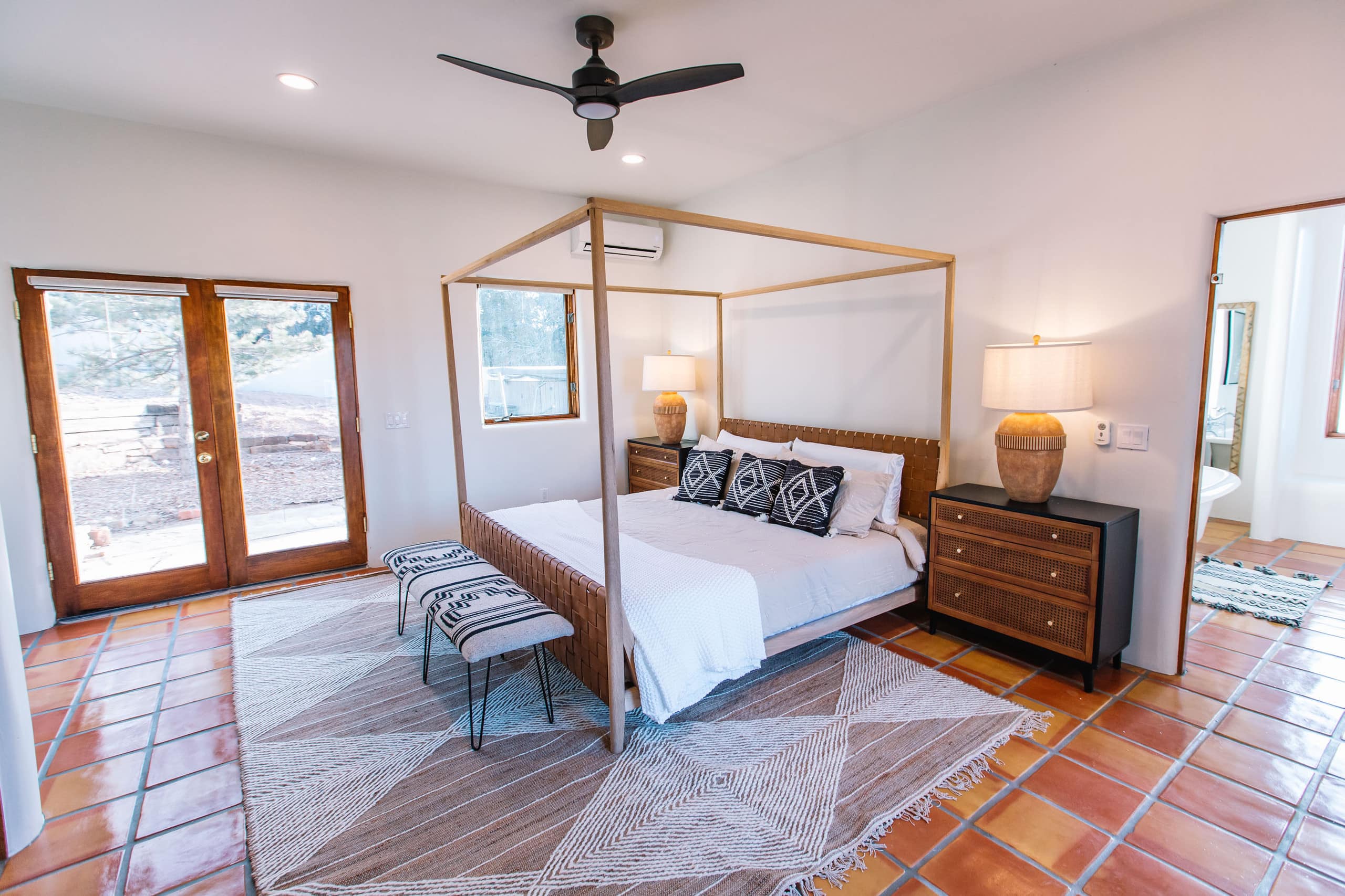 King suite with light-wood canopy bed and French doors