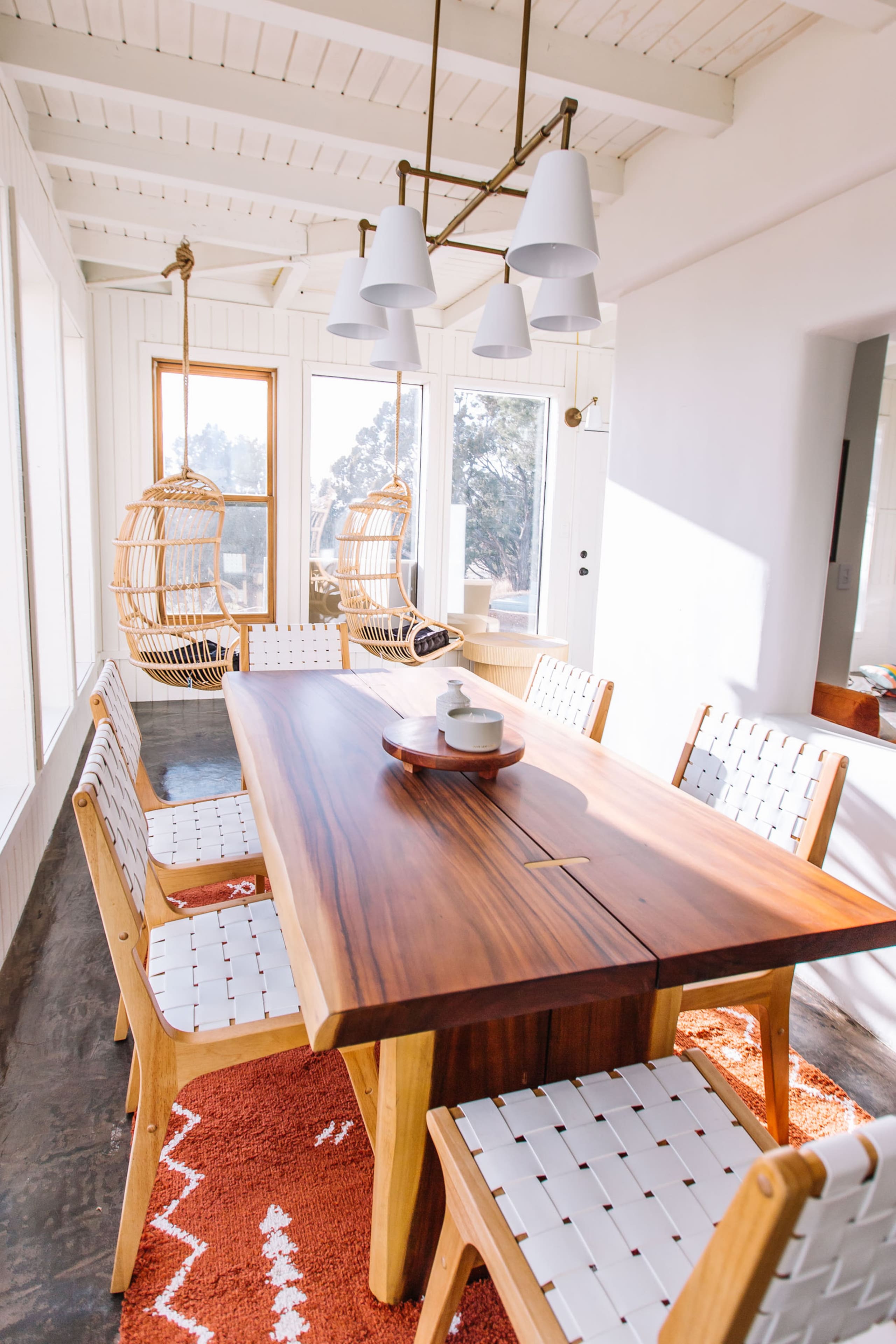 Sunroom dining with live-edge table and hanging egg chairs
