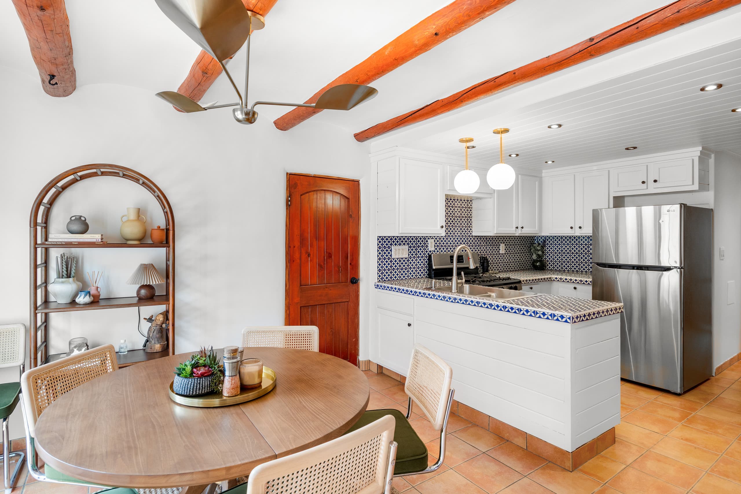 Casita kitchenette and dining with blue-tile peninsula and red door