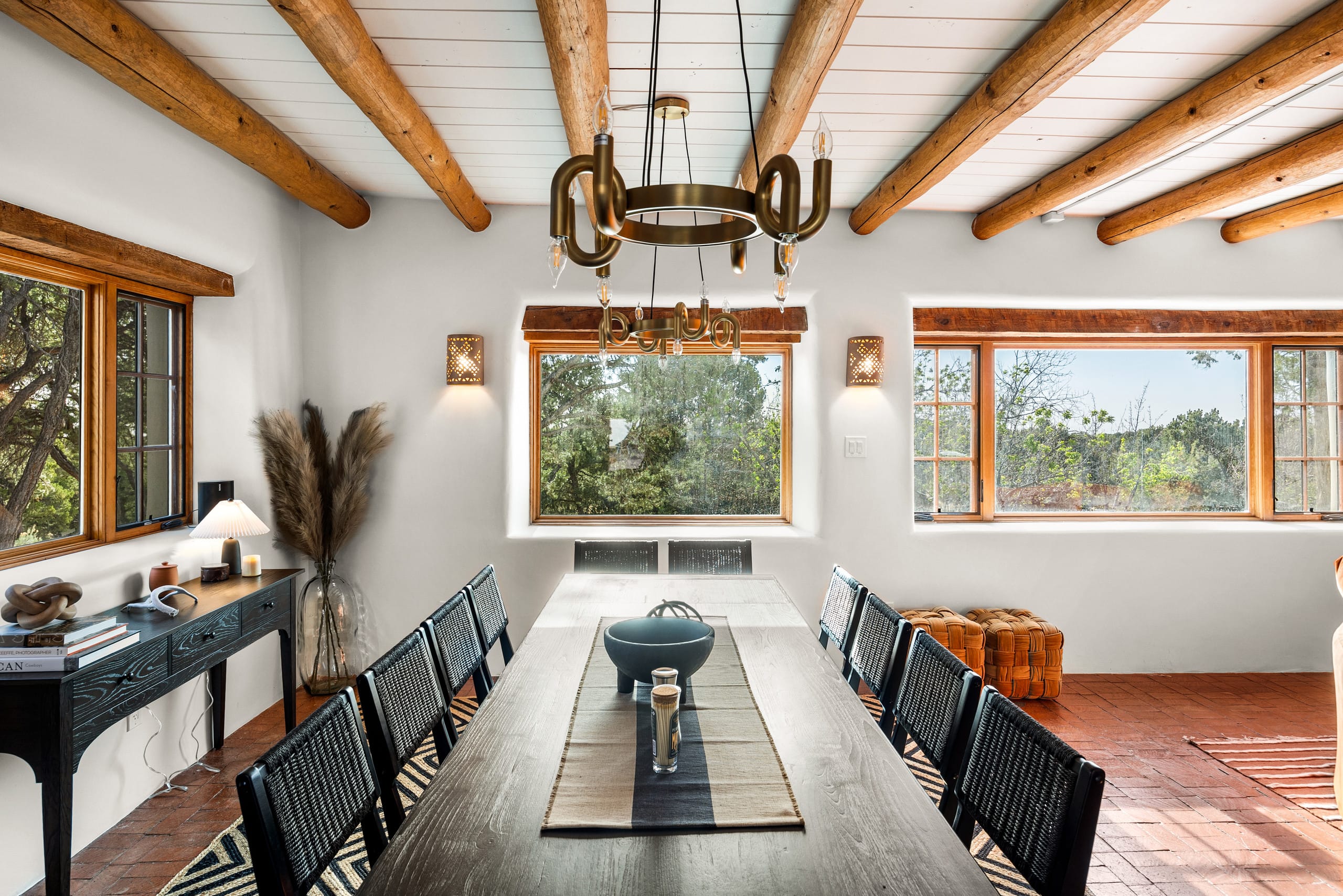Formal dining room with long table under twin brass chandeliers