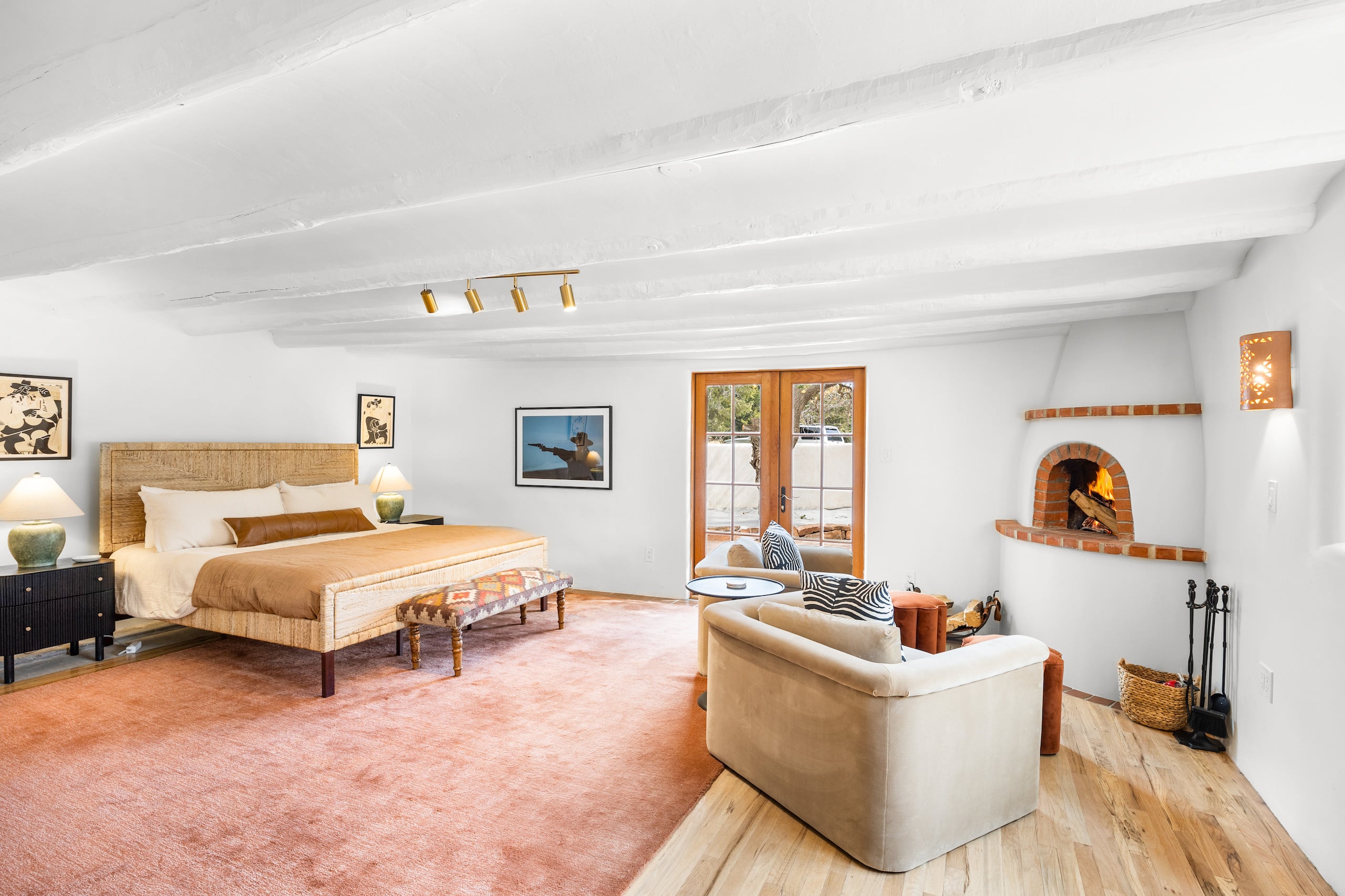 King bedroom with woven headboard, cowboy art, and French doors