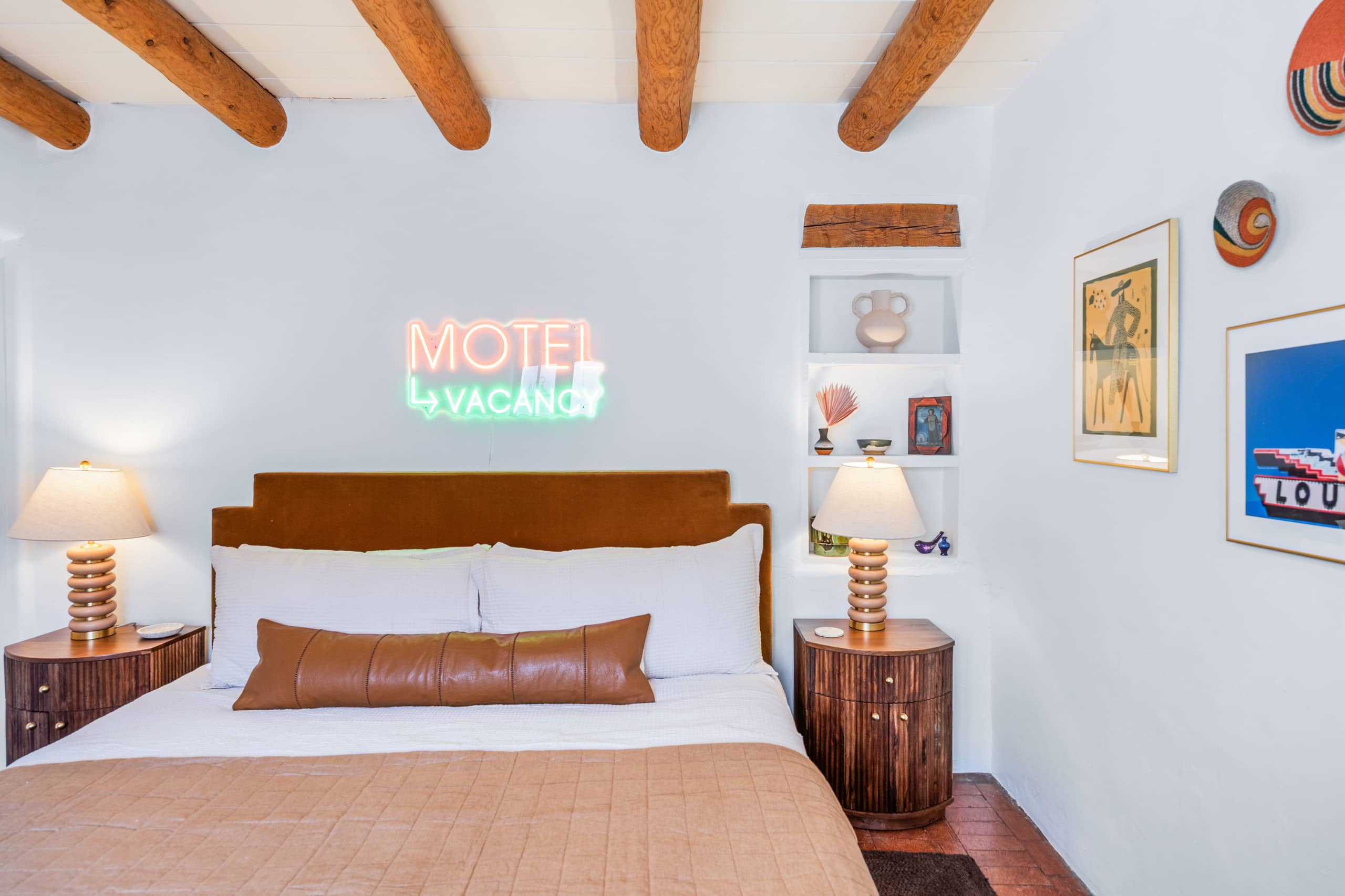 King bedroom with neon MOTEL sign and velvet headboard