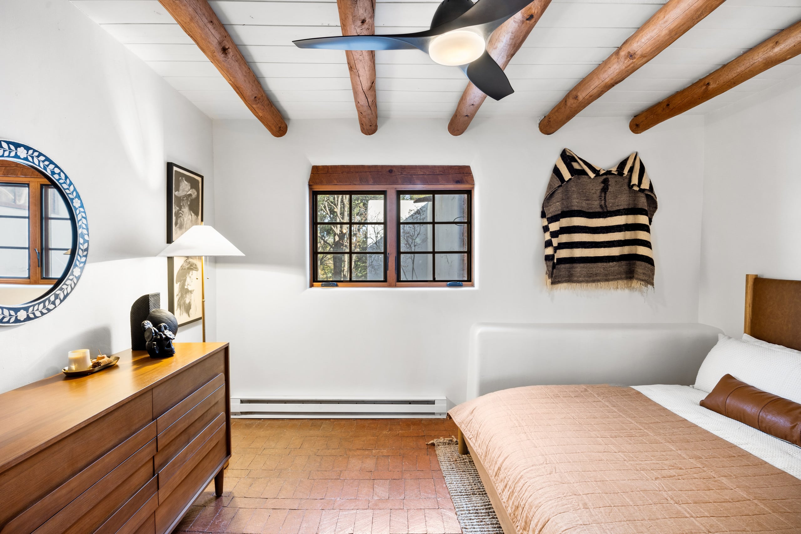 King bedroom with walnut dresser and striped serape wall hanging