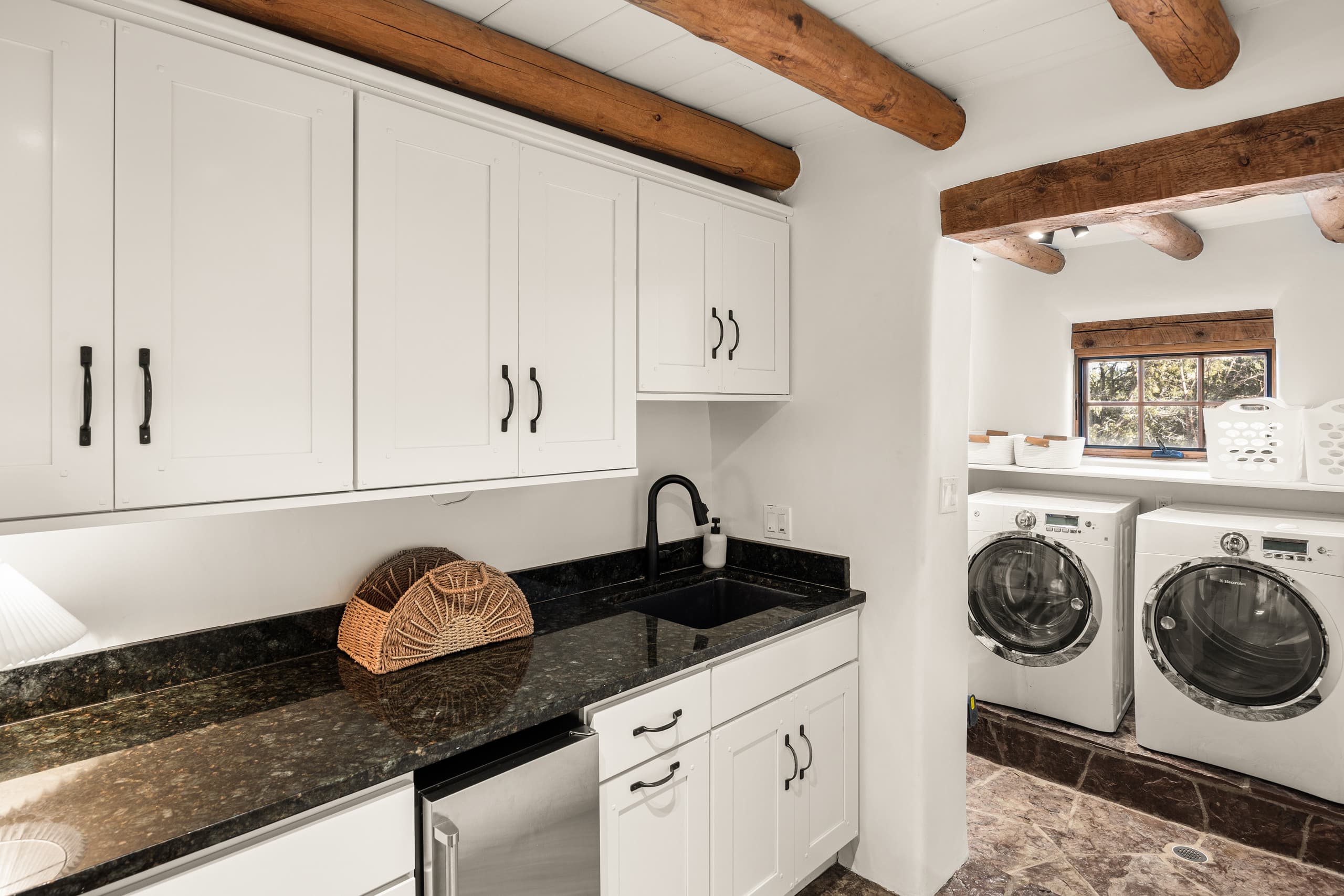 Laundry room with granite counters under wood beams
