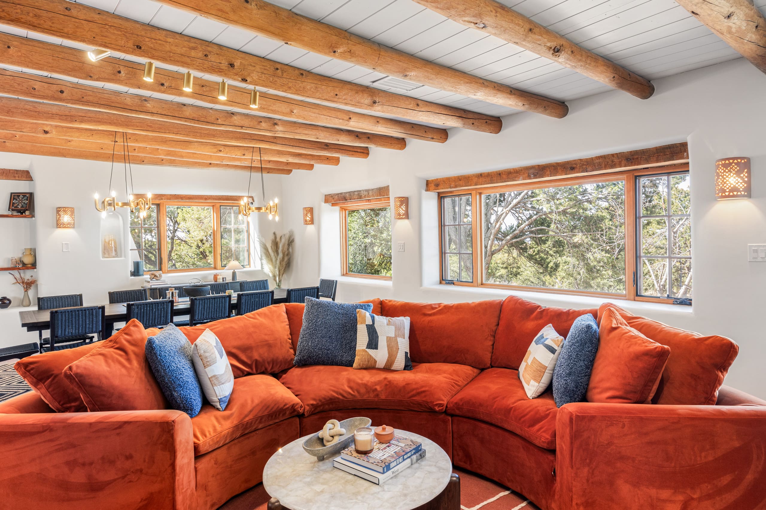 Main living room with orange sectional, white brick, and lit kiva fireplace