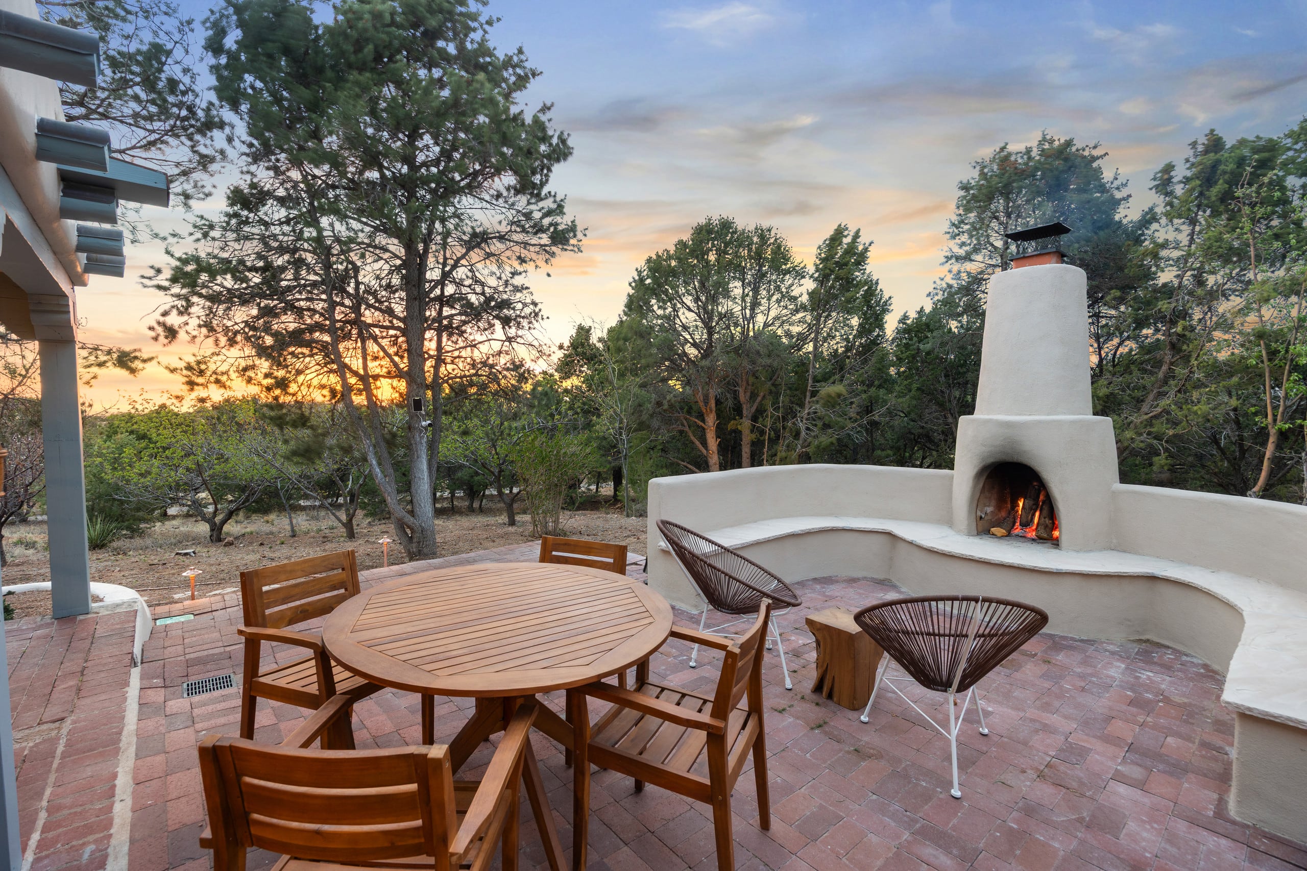 Outdoor kiva fireplace patio at sunset with dining table