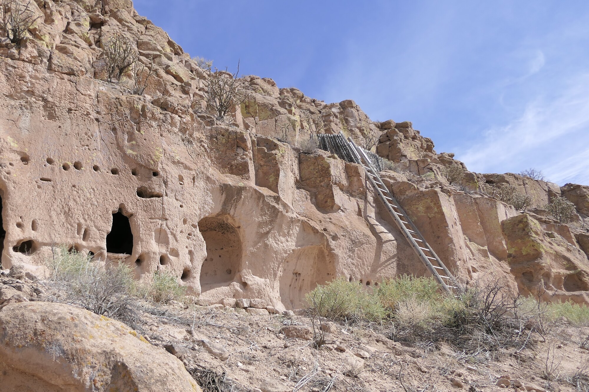 The carved cave dwellings and ladder on the cliff face at Puye